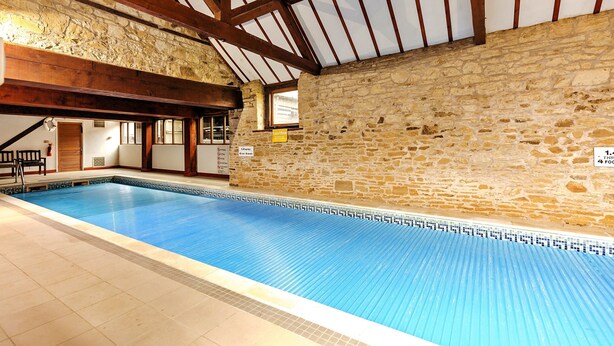 Una piscina interior con paredes de piedra y vigas de madera.