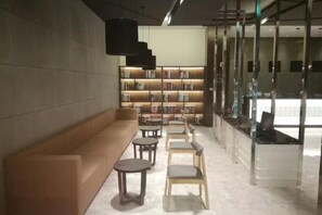 Ein stilvoller Lounge-Bereich mit einer Couch, Sesseln und einem Bücherregal.
