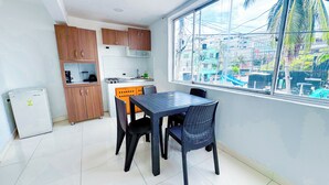 Una cocina compacta con armarios de madera, un refrigerador pequeño y una mesa de comedor con sillas.