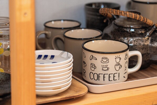 A kitchen area with ceramic mugs, plates, and a tea kettle. - KAYO.NIJO (Kyoto)