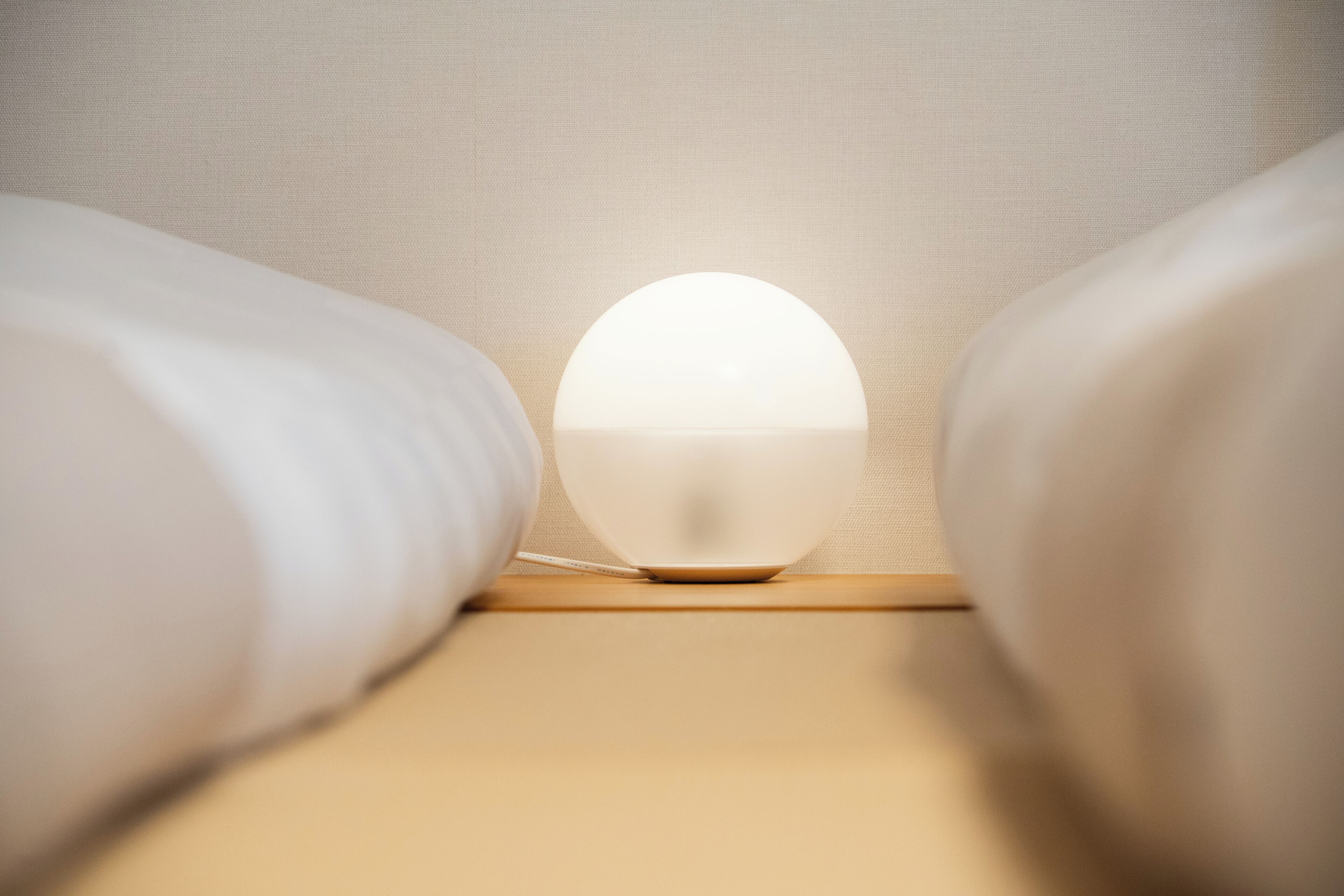 Una mesita de noche con una lámpara blanca en una habitación de hotel.