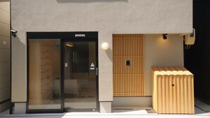 Un bâtiment doté d’une entrée avec une porte en verre, d’un mur en bois à lattes et d’une petite structure en bois.