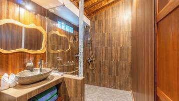 A modern bathroom with a stone sink, wooden vanity, and a shower area.