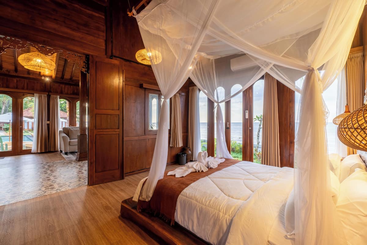 Une chambre spacieuse avec un grand lit, un plancher en bois et une vue sur l’extérieur.
