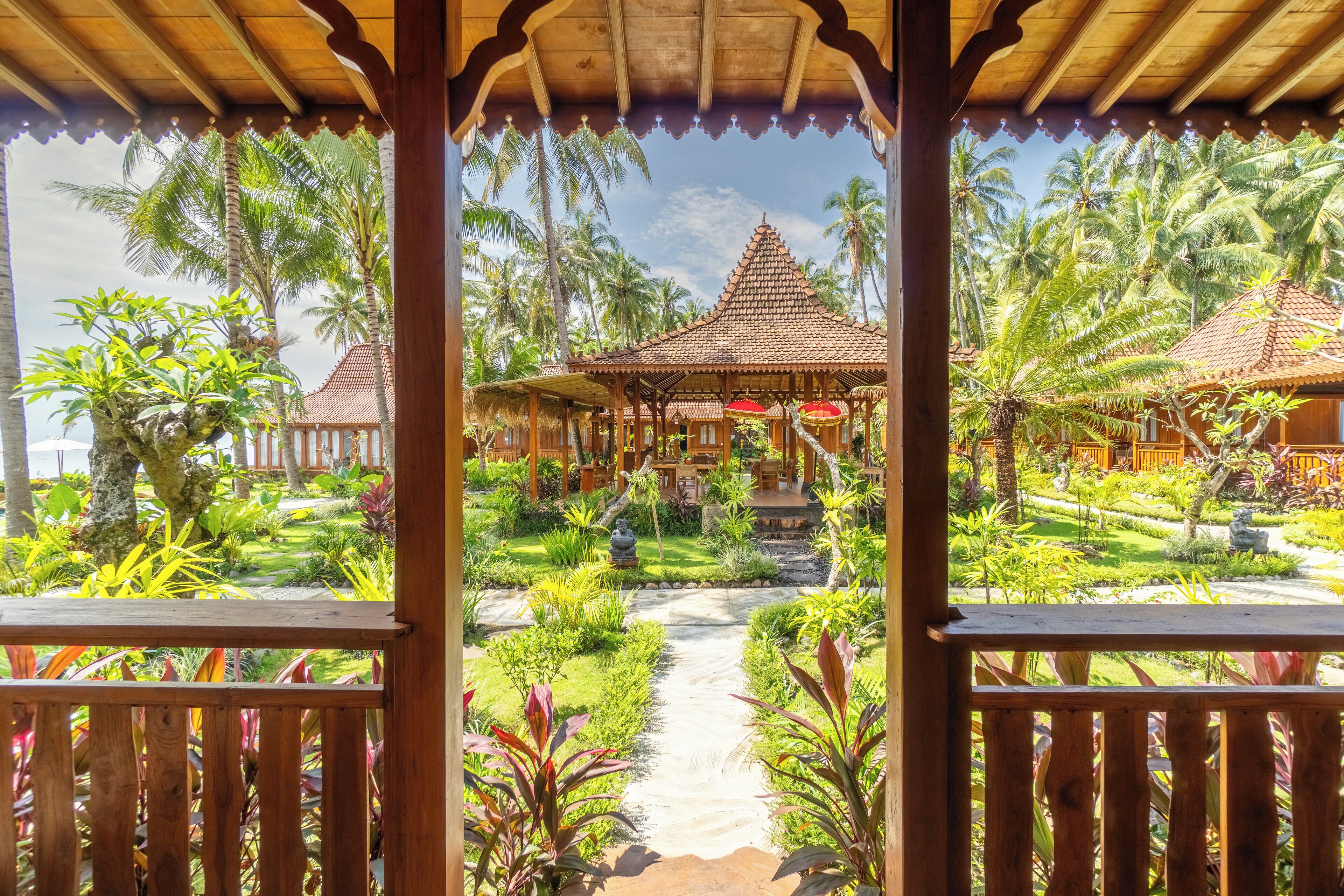 Ein tropisches Resort mit überdachtem Gang, Palmen und traditionellen Hütten.
