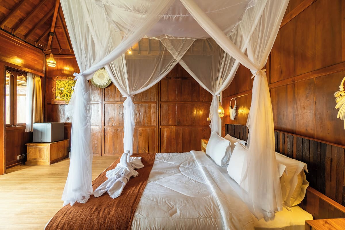 Une chambre spacieuse avec un grand lit, des murs en bois et un lit à baldaquin.