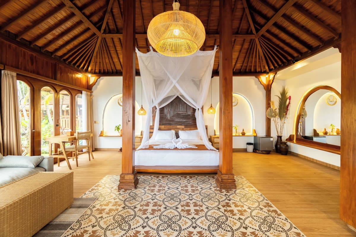 Une pièce spacieuse avec un grand lit, un plafond en bois et un tapis à motifs.