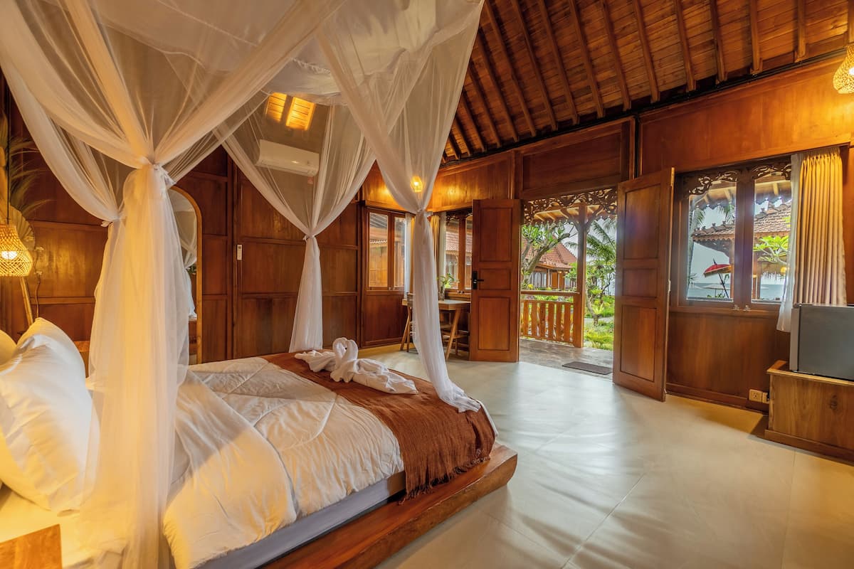 Une chambre spacieuse avec un grand lit, des murs en bois et une vue sur l’extérieur.