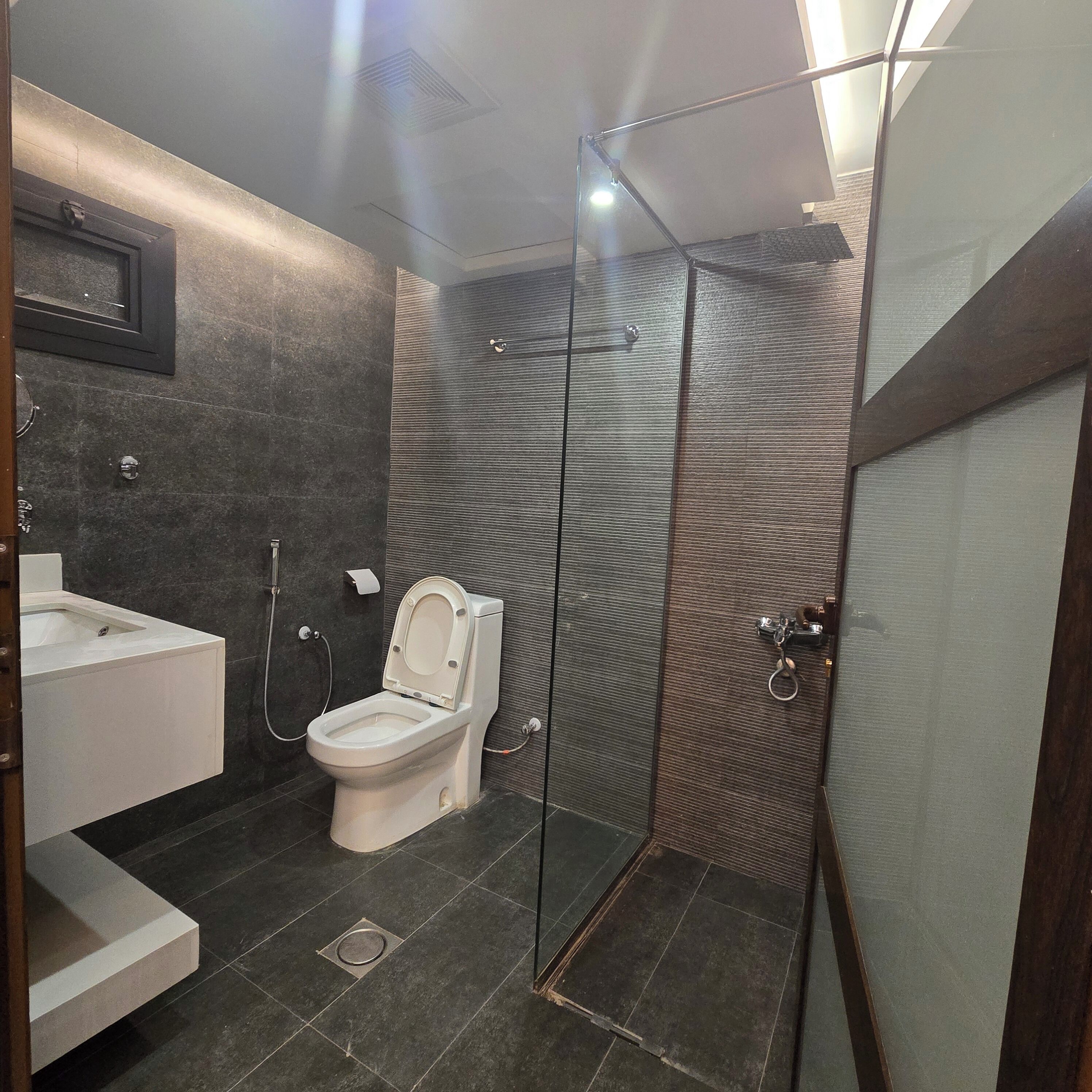 Ein modernes Badezimmer mit Duschkabine aus Glas, Toilette und Waschbecken.