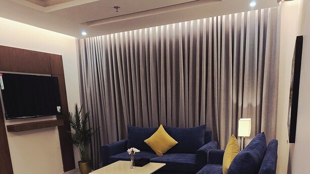 Ein modernes Wohnzimmer mit einem blauen Sofagarnitur, einem Couchtisch und einem großen Fenster mit Vorhängen.