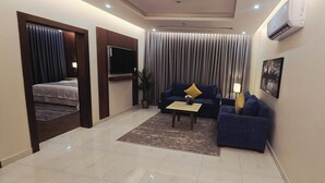 Ein modernes Hotelzimmer mit einem Bett, einer Couch, einem Couchtisch und einem Fernseher.