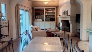 A cozy living room with a fireplace, a bookshelf, and a dining area.