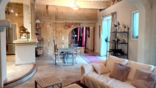 A spacious living area with a stone archway leading to a kitchen, a dining area, and a cozy seating area with a sofa and a coffee table.