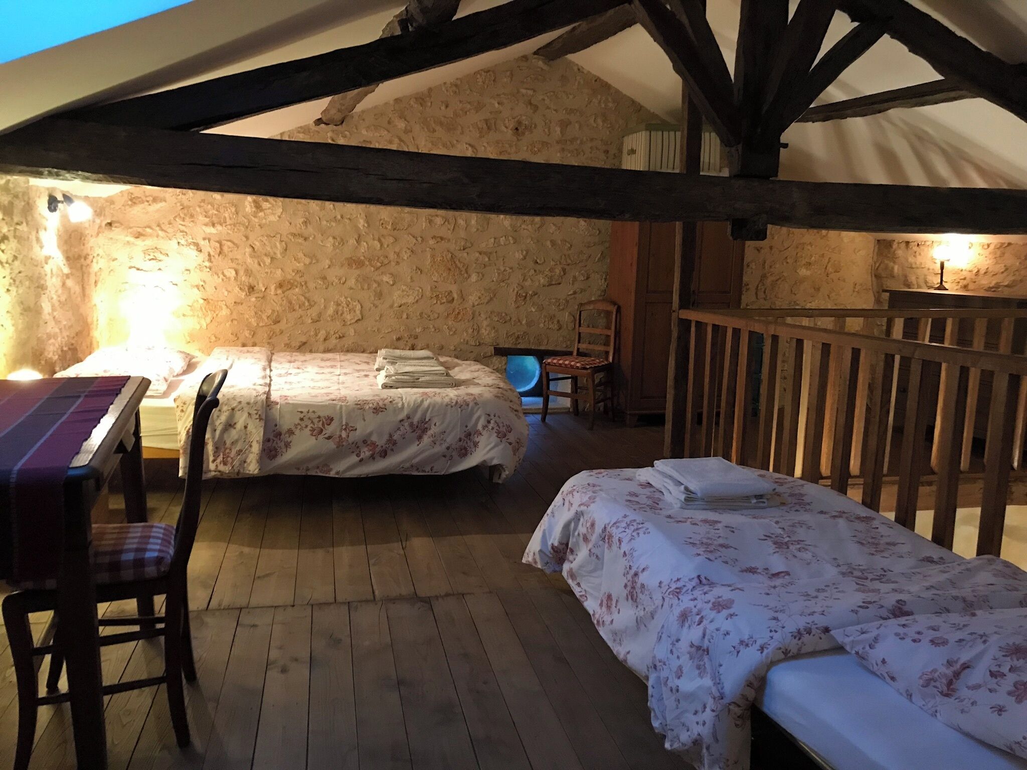 A rustic room with two beds, wooden furniture, and stone walls.