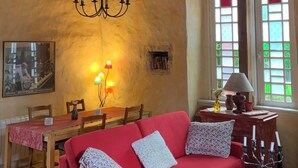 Ein gemütliches Wohnzimmer mit einem roten Sofa, Holzbalken, einer Chandelier und einem Essbereich.