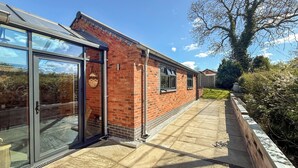 A modern house with a brick exterior, large glass doors, and a paved patio.