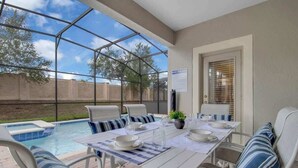 Eine überdachte Terrasse mit Pool, Sitzgelegenheiten im Freien und einem Tisch, der zum Essen gedeckt ist.