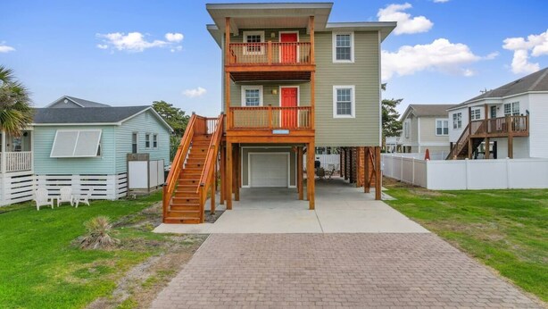 Une maison à deux étages avec un porche à l’avant, un escalier et un garage.