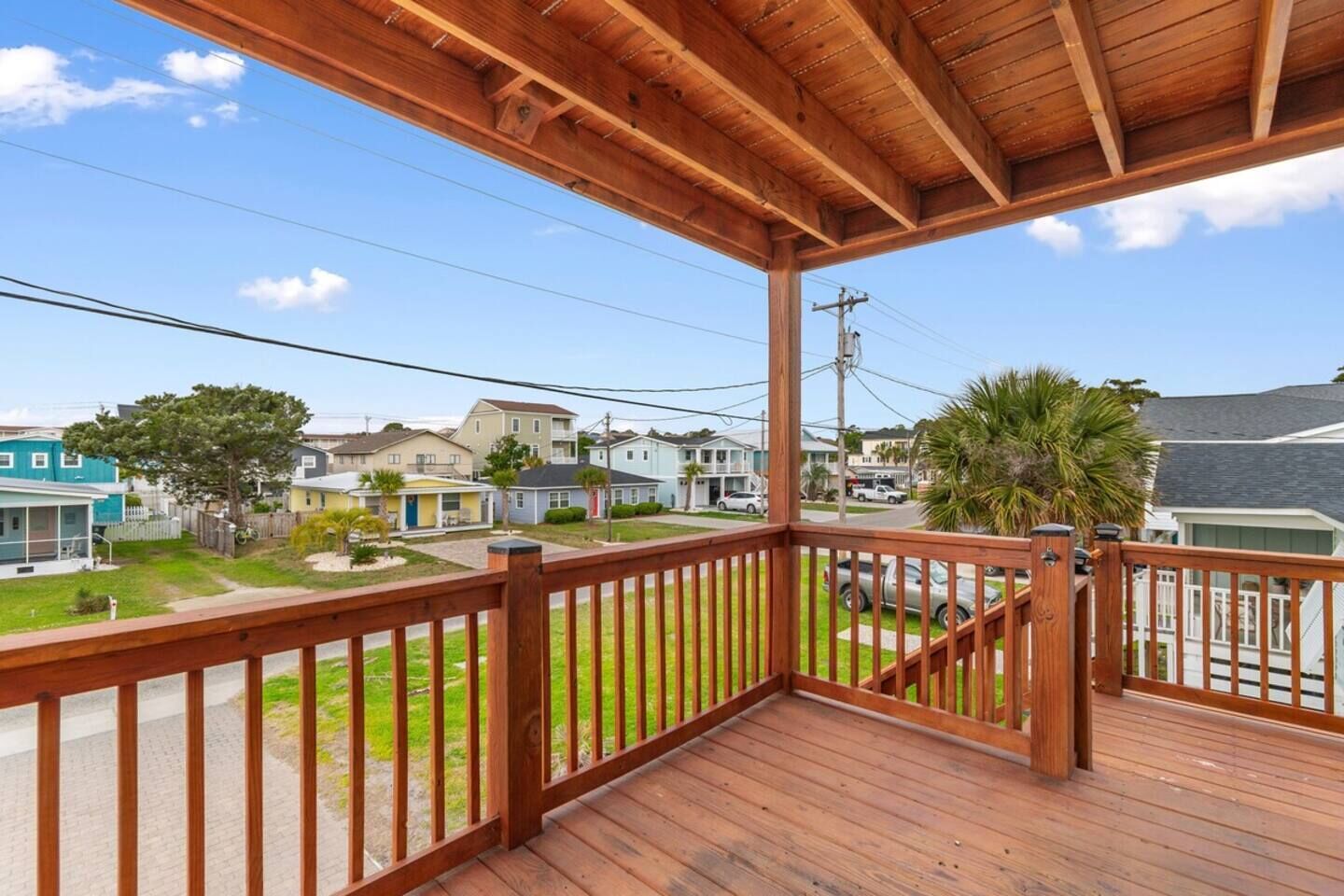 Une terrasse en bois avec une balustrade donnant sur une rue résidentielle.