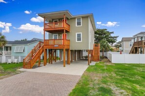 A two-story house with a wooden deck and a staircase leading to the upper level. - 5 BR Dog Friendly Home- Slps 12- Steps from sand (North Myrtle Beach)