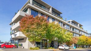 A modern multi-story building with balconies, large windows, and a tree in front. - Vibrant Stay with Lakeside Charm in Kingston (Kingston)
