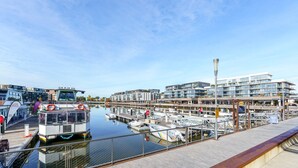 A marina with boats docked, a modern building with glass windows, and a clear blue sky. - Vibrant Stay with Lakeside Charm in Kingston (Kingston)