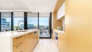 A modern kitchen with a large island, a view of the city through large windows, and a balcony. - Vibrant Stay with Lakeside Charm in Kingston (Kingston)