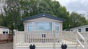 A mobile home with a covered porch, a small deck, and a mailbox. - 15 Willow Wynd Thurston Manor (Dunbar)