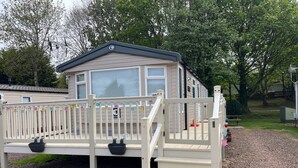 A mobile home with a porch, steps, and a fenced deck area. - 15 Willow Wynd Thurston Manor (Dunbar)