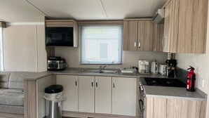 A compact kitchen with a microwave, toaster, and coffee maker, a sink, and a fire extinguisher. - 15 Willow Wynd Thurston Manor (Dunbar)