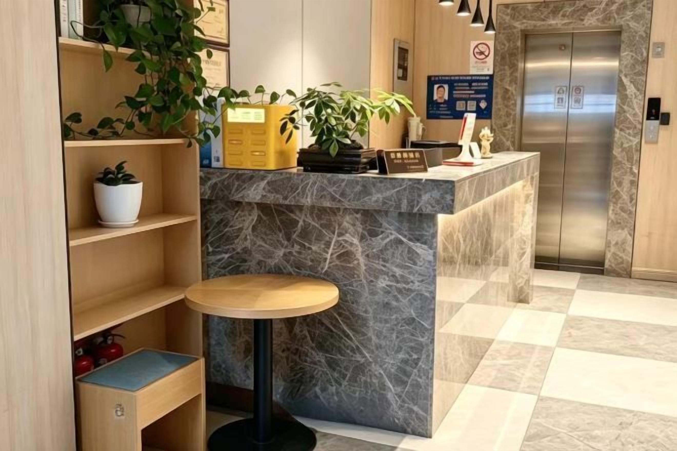 Un espace d’accueil avec un comptoir en marbre, une petite table ronde et une plante en pot.