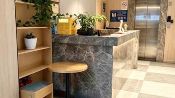 Un espace d’accueil avec un comptoir en marbre, une petite table ronde et une plante en pot.
