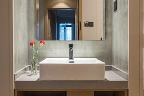 A bathroom with a white sink, a mirror, and a vase with red flowers. - Fule Selected Hotel (Shanghai)