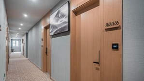 Ein Hotelgang mit Holztüren, einem gemusterten Teppich und einem gerahmten Kunstwerk an der Wand.
