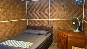 Une pièce comprenant un lit, un bureau en bois, une chaise et un mur orné d’un motif en chevrons.