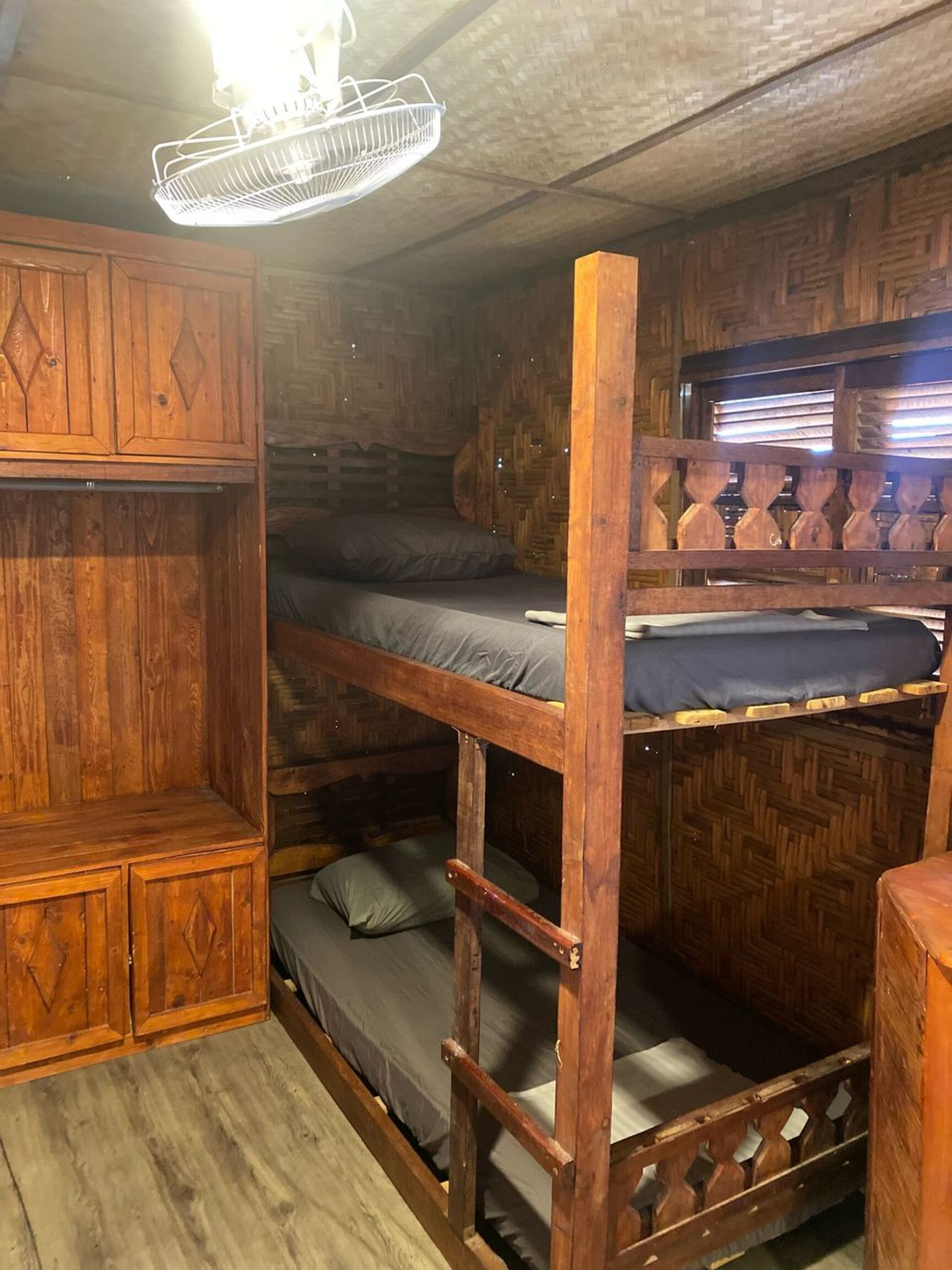 Habitación con literas, paredes de madera y ventilador de techo.