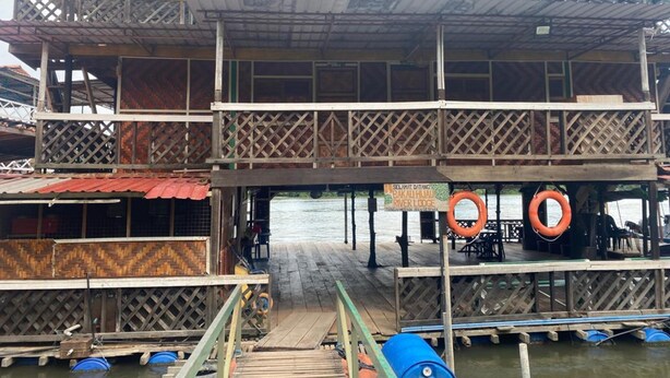 Une structure en bois à plusieurs niveaux, dotée d’une terrasse supérieure couverte, d’un panneau indicateur et de bouées de sauvetage.