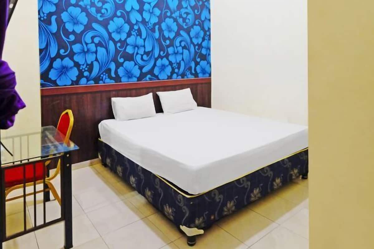Quarto com uma cama, mesa de cabeceira e uma cadeira.
