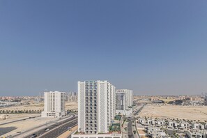 A high-rise building with multiple floors, surrounded by a desert landscape and other buildings. - Cozy Studio in Azizi Shaista Al Furjan (Dubai)