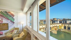 Ein Zimmer mit großem Fenster, das auf einen Fluss und Gebäude blickt, mit einem modernen Sessel und einer Stehlampe.