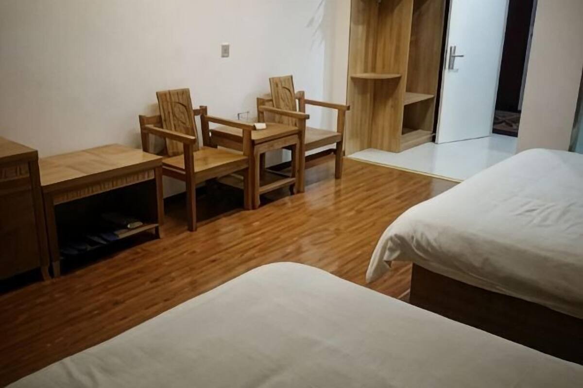 A room with two beds, a desk with chairs, and a wardrobe.