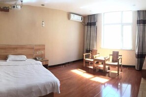 A hotel room with a bed, a desk, a chair, an air conditioning unit, and a window with curtains. - Xinle Dekaiyuan Express Hotel (Xinle)