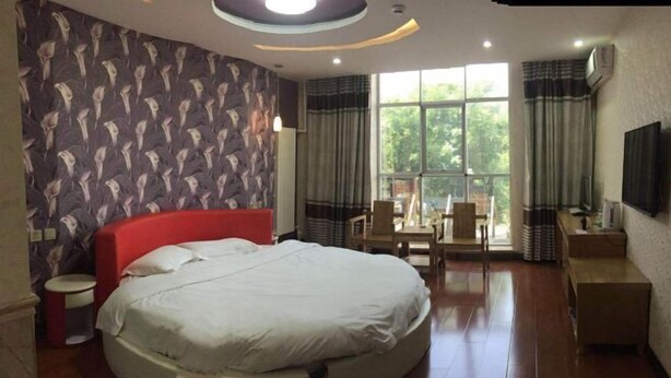 A modern bedroom with a large bed, a small round table, and a TV mounted on the wall. - Xinle Dekaiyuan Express Hotel (Xinle)