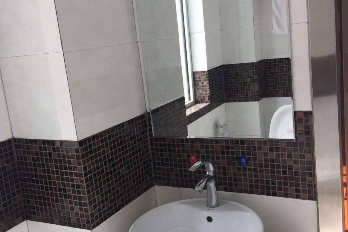 A bathroom with a white sink, a mirror, and a tiled wall with a dark border.