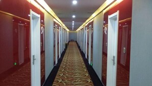 A hotel corridor with multiple doors on either side, carpeted floors, and overhead lighting. - Xinle Dekaiyuan Express Hotel (Xinle)
