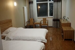 A hotel room with two beds, a wooden desk, a chair, a small table, and a window with curtains. - Xinle Dekaiyuan Express Hotel (Xinle)