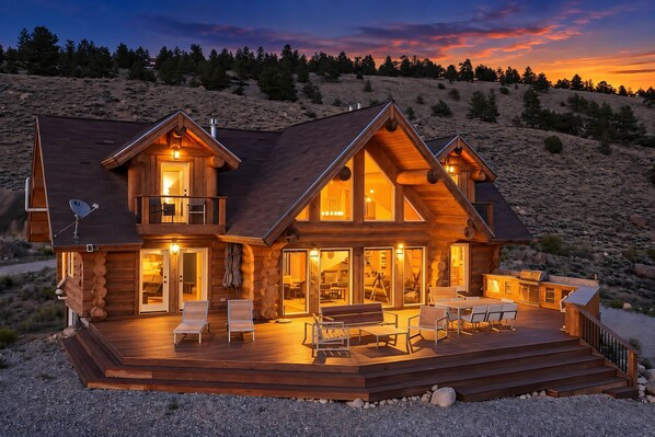 A log cabin with a deck, multiple rooms, and a large window.