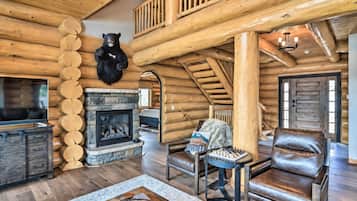 Interno di una baita di legno con camino in pietra, mobili in pelle e decorazione a testa di orso.