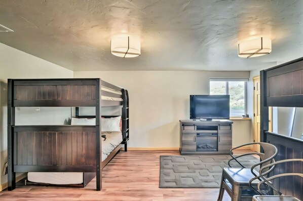 A room with bunk beds, a television, a desk, and a window.
