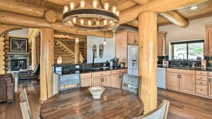 A rustic interior with a wooden dining table, a fireplace, and a kitchen area. - 4 BR Luxury Lakefront Cabin w/ Mtn Views (Lake County)